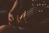 Moody close-up of a hand playing a guitar. Perfect for music-themed projects.