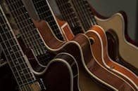 Detailed shot of diverse acoustic guitars lined up, showcasing strings and wood texture.